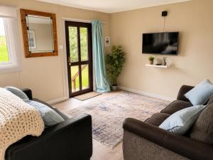 a living room with a couch and a tv at John D's Cabin Getaway in Derry Londonderry