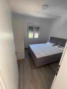 a white bedroom with a bed and a window at Rujovic 