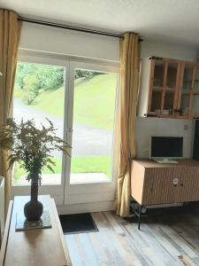 a living room with a large window and a computer on a table at Studio montagne in Mijoux