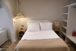 a bedroom with a bed with white sheets and shelves at Amber Apartments in Jávea