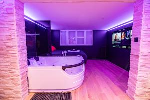 a large bath tub in a room with purple lighting at Cristal Room in Rochefort