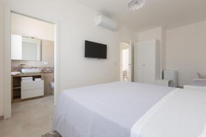 a white bedroom with a white bed and a bathroom at B&B Li Peticurti in Cerfignano