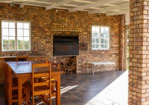 a room with a brick wall with a table and a television at Geluk Farmhouse in Somerset East