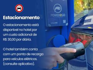 a hand holding a parking meter next to a car at Hotel Ilhas da Grécia in Guarujá