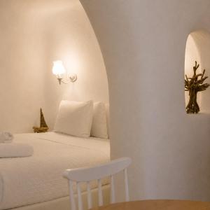 a bedroom with a white bed with a chair at SantoCaves in Akrotiri