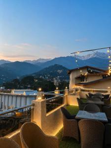 a balcony with chairs and tables with mountains in the background at The Zinnia Castle- Dharamshala # Centrally Heated & Air Cooled # Premium Rooms # Lift # Bar # Terrace # Big Parking # Near market # Top Rated # Property of the year in Dharamshala