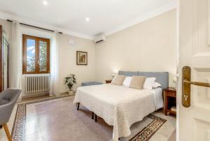 a white bedroom with a bed and a chair at TorripaCollection - Villa Livia - Bolsena Lake in Montefiascone