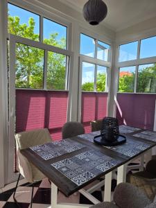 a dining room with a table and chairs and windows at Haus Deichvoigt in Cuxhaven