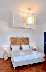 a bedroom with a white bed with two lamps at Aspro Mple in Astypalaia