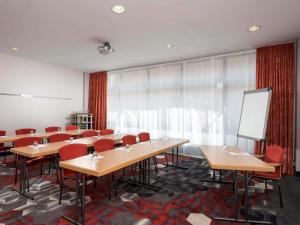 Ein Klassenzimmer mit Tischen, roten Stühlen und einer Tafel in der Unterkunft Mercure Hotel München Neuperlach Süd in München