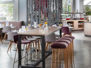 ein Esszimmer mit einem Holztisch und Hockern in der Unterkunft Mercure Hotel München Neuperlach Süd in München