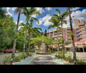 a fountain in front of a building with palm trees at Apartamento nas Termas no Apart-hotel in Gravatal