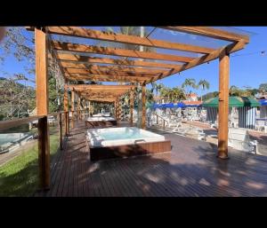 a wooden pergola with a swimming pool on a deck at Apartamento nas Termas no Apart-hotel in Gravatal