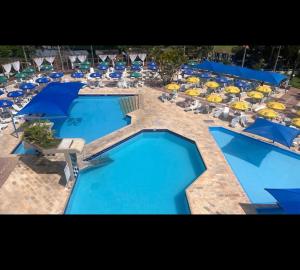 a group of blue swimming pools with chairs and umbrellas at Apartamento nas Termas no Apart-hotel in Gravatal