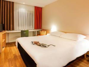 ein Schlafzimmer mit einem großen weißen Bett, auf dem ein Schuh steht in der Unterkunft Ibis Ulm City in Ulm + 44 Fotos