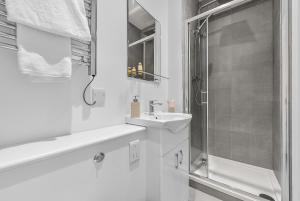 a white bathroom with a sink and a shower at Newly Reopened, Modern Flat Central Location in Staines