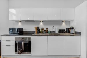a kitchen with white cabinets and a stove top oven at Newly Reopened, Modern Flat Central Location in Staines