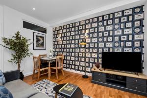 a living room with a tv and a wall of plates at Newly Reopened, Modern Flat Central Location in Staines