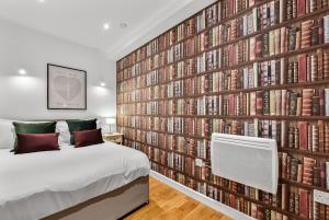 a bedroom with a large wall of books at Newly Reopened, Modern Flat Central Location in Staines