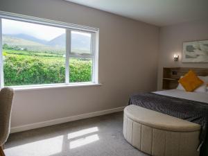 a bedroom with a bed and a window and a chair at Mountain View Cottages in Tralee