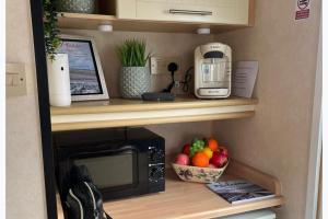 a microwave and a bowl of fruit on a shelf at 2 Bedroom Caravan - Sleeps 6 - Parking Seaside in Abergele