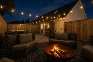 a patio with couches and a fire pit with lights at Hazel Cottage in Tenby