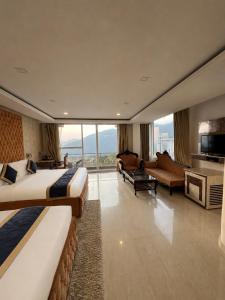 a hotel room with two beds and a living room at The Zinnia Castle- Dharamshala # Centrally Heated & Air Cooled # Premium Rooms # Lift # Bar # Terrace # Big Parking # Near market # Top Rated # Property of the year in Dharamshala
