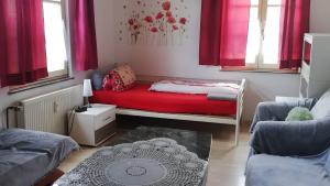a small room with a red bed and two windows at Haus Lindheim in Altenstadt