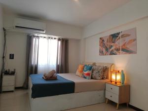 a bedroom with a bed and a lamp and a window at Affordable Travellers Studio Condo near Mactan Airport by A&C in Pusok