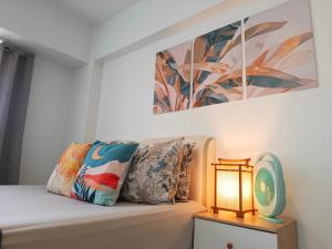 a room with a bed with a lamp and a painting at Affordable Travellers Studio Condo near Mactan Airport by A&C in Pusok