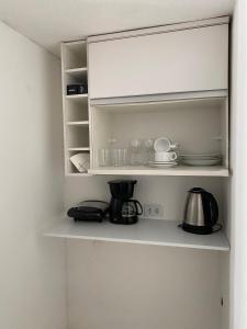 a kitchen shelf with a coffee maker and a tea pot at Apartamento em Condomínio - Centro de Búzios in Búzios