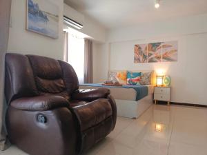 a living room with a leather chair and a bed at Affordable Travellers Studio Condo near Mactan Airport by A&C in Pusok