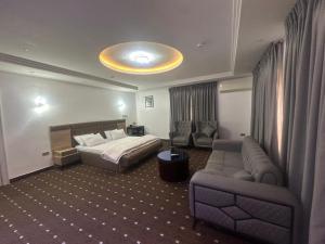 a hotel room with a bed and a couch at Peev Apartments in Abuja +5 photos