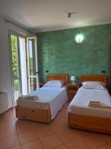 two beds in a bedroom with a green wall at La Porta del Lugana - Albergo Quattro Pini in Pozzolengo