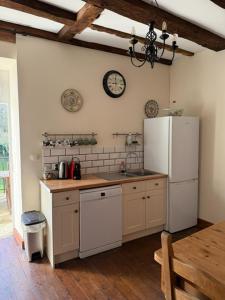 a kitchen with a white refrigerator and a clock on the wall at Chez le Cavalier in Génis