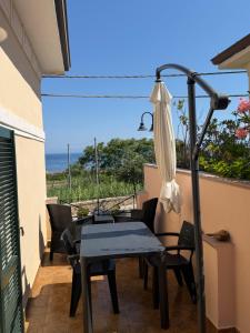 a patio with a table and chairs and an umbrella at A Due Passi da MicheIino in Parghelia