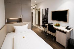 a bedroom with a bed and a desk and a television at Manhattan Hotel in Frankfurt