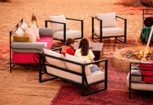 two women sitting in beds next to a fire at Luxury cMp in Al Karāmah