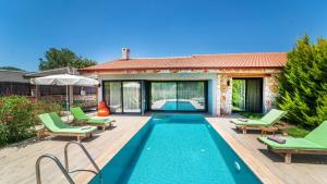 a swimming pool with green chairs and a house at Villa Lagerta in Kayakoy
