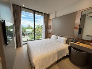 a hotel room with a bed and a large window at Palm Hotel in Tam Kỳ