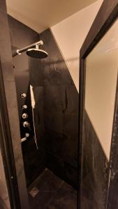 a bathroom with a shower with black tile and a mirror at 4 Rest in a warm and comfortable loft in Coihaique