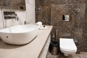 a bathroom with a white sink and a toilet at Hotel Emience in Chandīgarh +17 photos