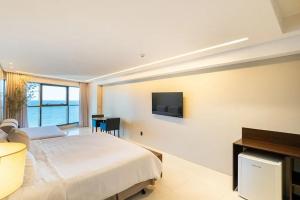 a bedroom with a bed and a tv on the wall at HY BEACH FLATS - INTERNATIONAL in Recife