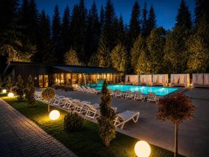 a swimming pool with tables and chairs and lights at NACHIKU Bukovel Resort & SPA in Palyanytsya