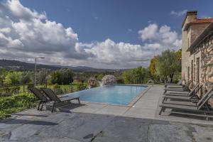 a swimming pool with two chairs next to a building at Casa Valxisto in Penafiel