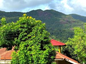 a tree in front of a house with mountains in the background at Duplex villa in Khlaung Phai Bae