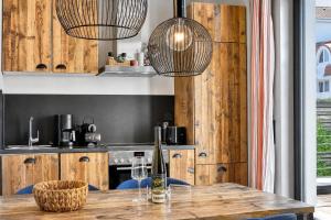 a kitchen with wooden cabinets and a table with two lights at Ferienwohnung Heimathafen Villa Martha Binz in Binz