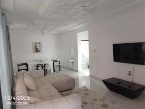 a white living room with a white couch and a tv at Chemba's Paradise in Galu