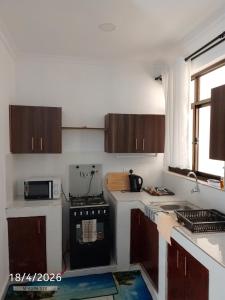 a kitchen with wooden cabinets and a black stove at Chemba's Paradise in Galu