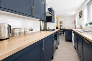 a kitchen with blue cabinets and a wooden counter top at Earp House - Allerton Liverpool Stay - Sleeps 7 in Liverpool